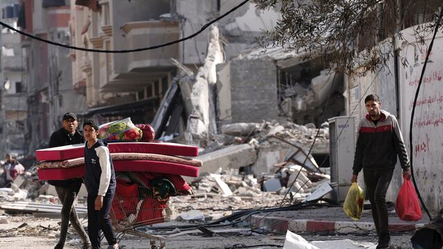 Palestinos caminan por zonas destrozadas por bombardeos israelíes en el campo de refugiados de Nusseirat, en la Franja de Gaza, el martes 16 de enero de 2024.