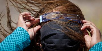Una mujer con anteojos especiales para ver un eclipse solar total en Piedra del Águila, Neuquén, Argentina