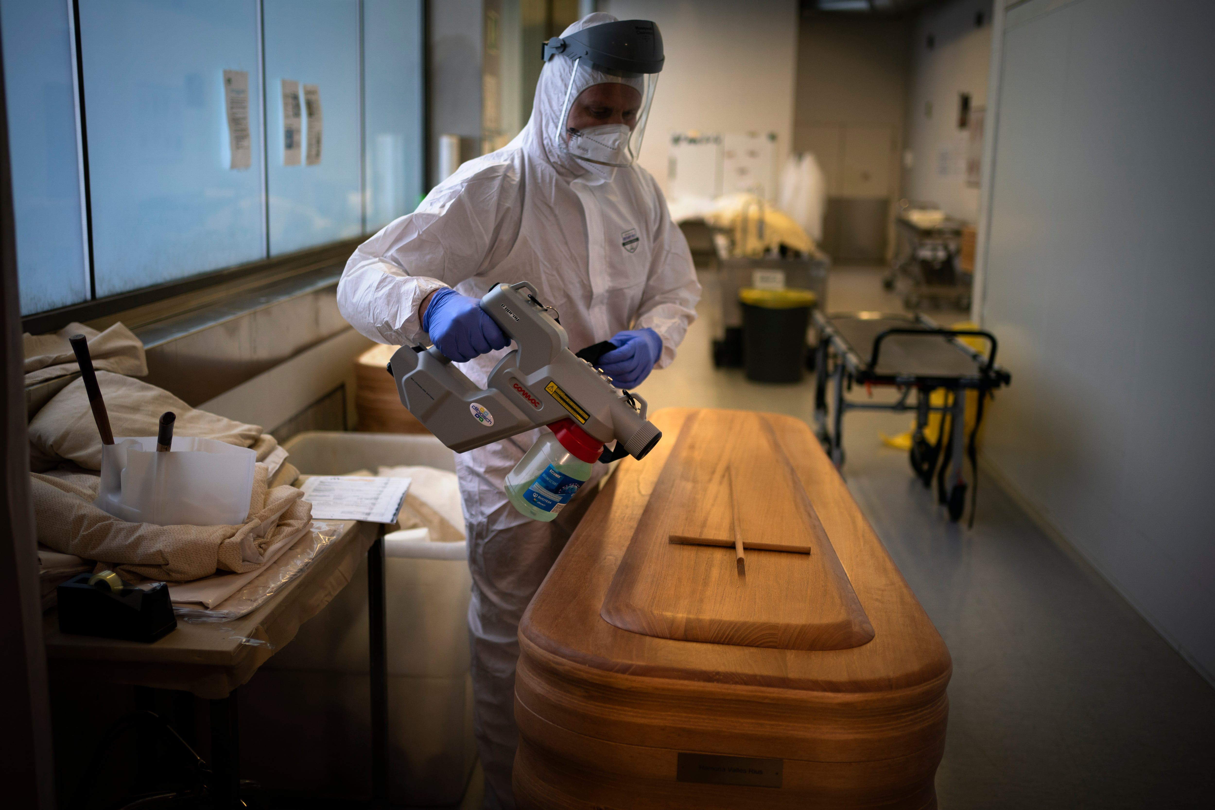 ARCHIVO - Un trabajador de una funeraria desinfecta un ataúd con el cuerpo de una persona que falleció a causa del COVID-19 antes de un funeral en el tanatorio Memora, en Girona, España, el 4 de febrero de 2021. (AP Foto/Emilio Morenatti, archivo)