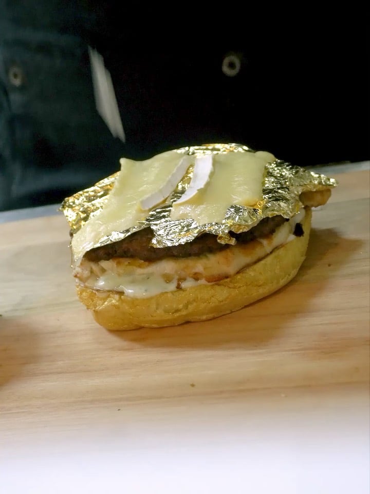La hamburguesa tiene dos proteínas, queso brie, nueces, salsas, mayonesa picante, cebolla y más.