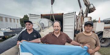 Owen Crippa, sosteniendo la bandera argentina, junto con los mecánicos del avión que estuvieron en Malvinas