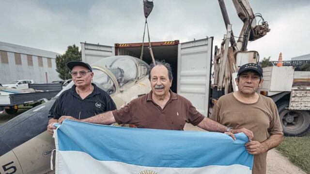 Owen Crippa, sosteniendo la bandera argentina, junto con los mecánicos del avión que estuvieron en Malvinas