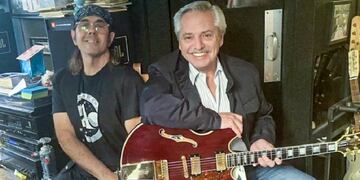 Alberto Fernández probando una guitarra junto a un músico de David Bowie