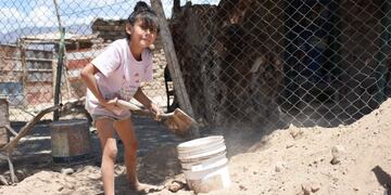 La pequeña junto a su padre Mario, a quien ayuda en la ardua tarea de levantar su casita