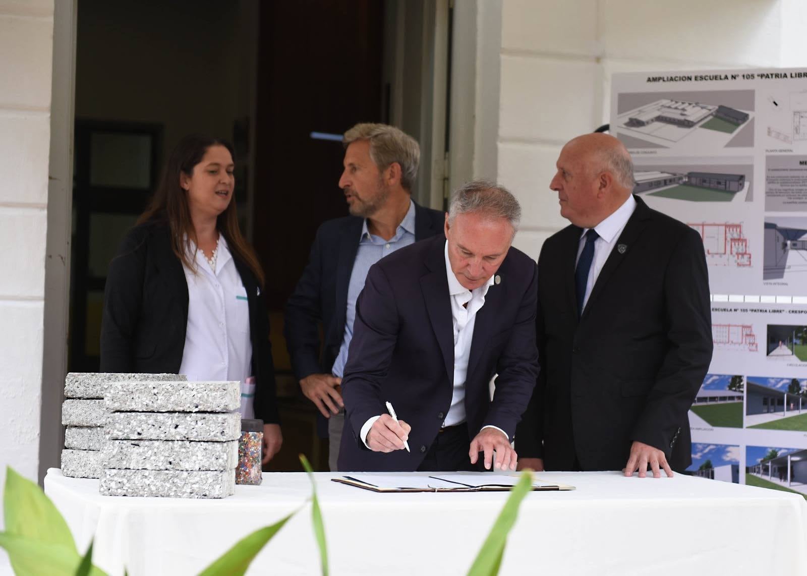 Darío Schneider, ministro de Planeamiento, Infraestructura y Servicios firmando acuerdos junto al Gobernador Frigerio y autoridades de educación.