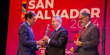 El gobernador Carlos Sadir hace entrega de la estatuilla del Premio San Salvador al Dr. Ramón Alfonso Exeni. Con ellos, el intendente Raúl Jorge en el escenario del Centro Cultural "Éxodo Jujeño".