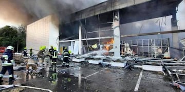 Los bomberos intentando apagar las llamas tras el ataque al centro comercial de Kremenchuk.