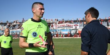 El árbitro del encuentro, José Carreras, le muestra al técnico de Deportivo Maipú, Juan Sara, el cartucho de bengala que impactó en el arquero visitante. / José Gutiérrez ( Los Andes).