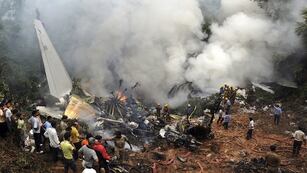 ARCHIVO - Civiles observan a bomberos y rescatistas trabajar en el lugar donde se estrelló un avión de Air India en Mangalore, en el estado de Karnataka, en el sur de India, el sábado 22 de mayo de 2010. (AP Foto, archivo)