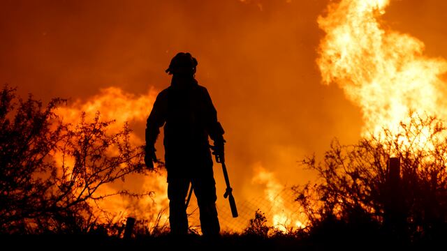 La silueta de un bombero se recorta sobre las llamas que arrasan un bosque en un incendio a las afueras de Villa Carlos Paz, Argentina, el 10 de octubre de 2023. (AP Foto/Nicolás Aguilera)