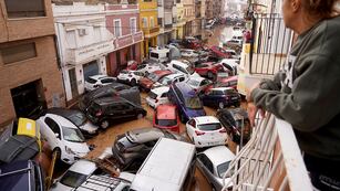 Una mujer mira desde su balcón mientras varios vehículos quedan atrapados en la calle tras las inundaciones en Valencia, el miércoles 30 de octubre de 2024. (Foto AP/Alberto Saiz)
