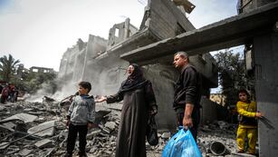 Palestinos recopilan sus pertenencias entre los escombros de un edificio residencial tras un ataque aéreo israelí en el campo de refugiados de Maghazi, en el centro de la Franja de Gaza, el 29 de marzo de 2024.