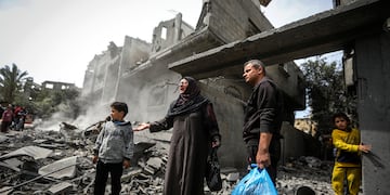 Palestinos recopilan sus pertenencias entre los escombros de un edificio residencial tras un ataque aéreo israelí en el campo de refugiados de Maghazi, en el centro de la Franja de Gaza, el 29 de marzo de 2024.