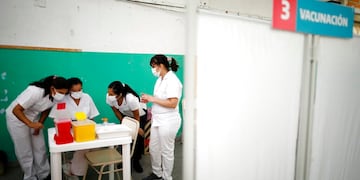 Enfermeras leen las instrucciones para inyectar las vacunas Sputnik V contra el COVID-19 en la escuela pública Bernal, a las afueras de Buenos Aires, Argentina