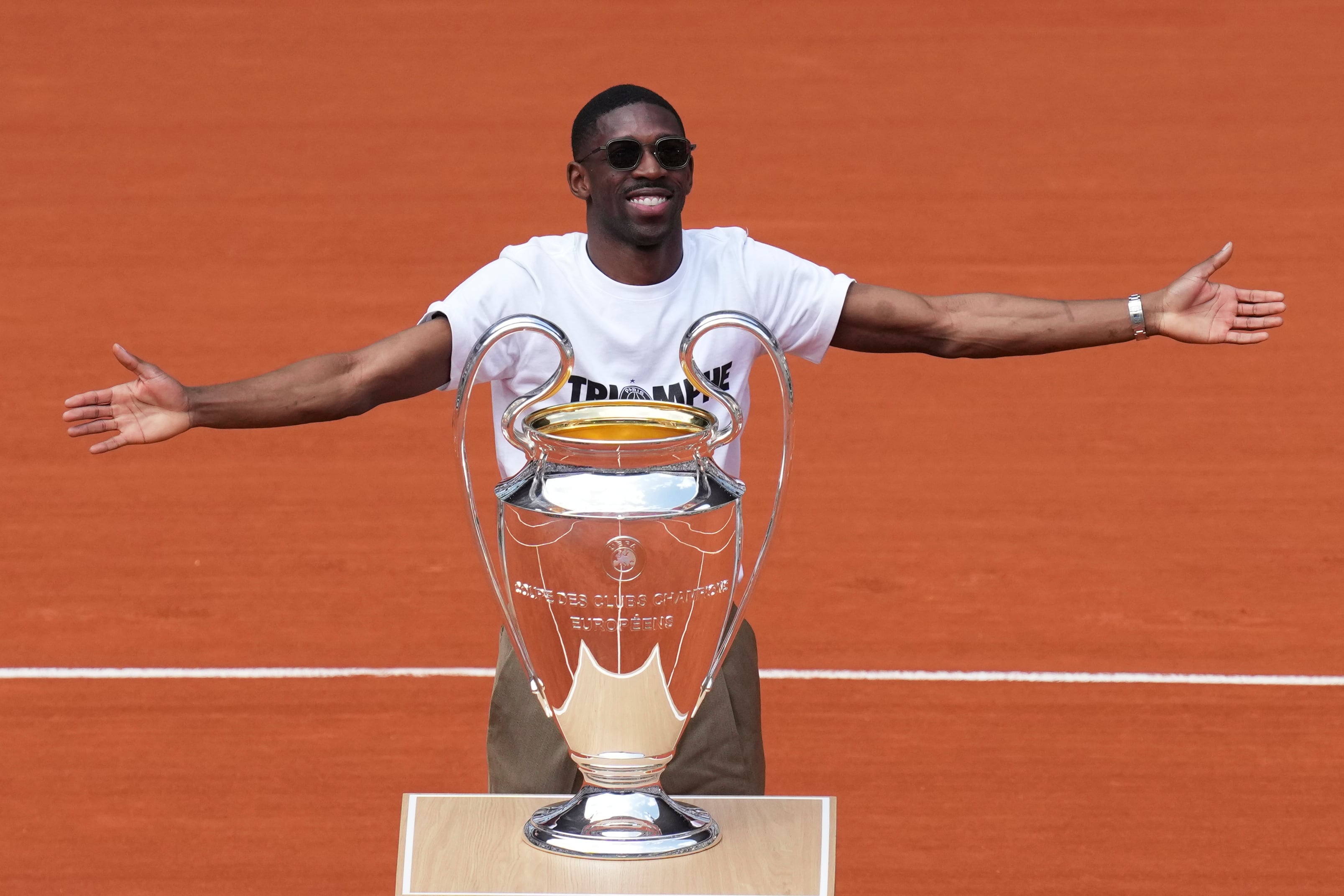 Ousmane Dembélé, delantero del Paris Saint-Germain, muestra el trofeo de la Liga de Campeones en el estadio principal del Abierto de Francia, el lunes 2 de junio de 2025. (AP Foto/Christophe Ena)