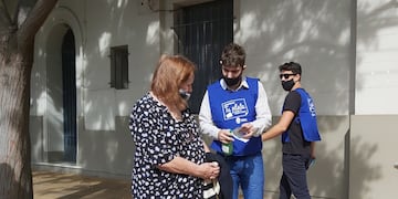 En la vereda del banco enseñando a los mayores a usar más frecuentemetne la tarjeta de débito para evitar estafas.