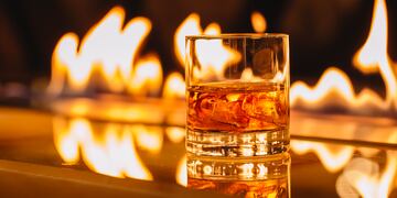 side view of glass of whiskey with ice on a background of a burning flame