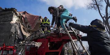Bomberos rescatan a una mujer atrapada en un edificio residencial de la ciudad de Mariúpol. Foto: AP Photo/Evgeniy Maloletka.