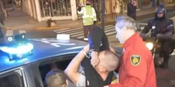 El hombre detenido intentando escapar por la ventana del patrullero.