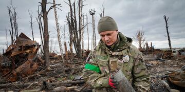 Un militar del Ministerio del Interior recoge proyectiles sin explotar, granadas, minas, después de las recientes batallas en Hostomel cerca de Kiev. (AP/Efrem Lukatsky)