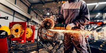 A metal industry worker processing armature with grinder at factory.
Industria Metalúrgica, Metalurgia