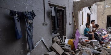 Palestinos sentados entre los escombros de una casa después de que fuera alcanzada por un bombardeo israelí en Khan Younis, en el sur de la Franja de Gaza, el domingo 29 de octubre de 2023.