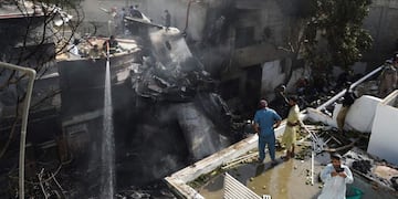 TOPSHOT - Firefighters spray water on the wreckage of a Pakistan International Airlines aircraft after it crashed at a residential area in Karachi on May 22, 2020\u002E - A Pakistani passenger plane with nearly 100 people on board crashed into a residential area of the southern city of Karachi on May 22\u002E (Photo by Rizwan TABASSUM / AFP)
