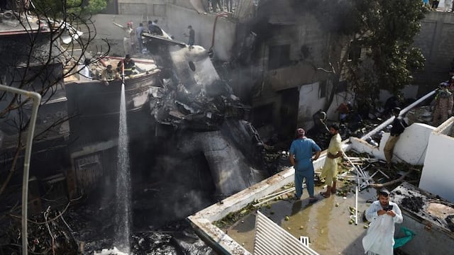 TOPSHOT - Firefighters spray water on the wreckage of a Pakistan International Airlines aircraft after it crashed at a residential area in Karachi on May 22, 2020\u002E - A Pakistani passenger plane with nearly 100 people on board crashed into a residential area of the southern city of Karachi on May 22\u002E (Photo by Rizwan TABASSUM / AFP)