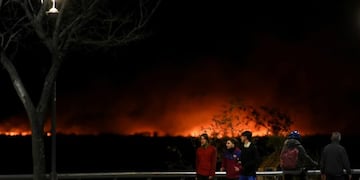 People jog as fire is seen along the shoreline of the Parana River in Rosario, Argentina July 30, 2020\u002E REUTERS/Stringer NO RESALES\u002E NO ARCHIVES