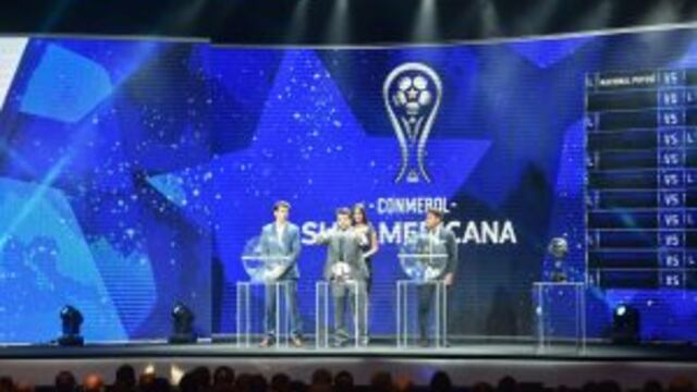 Conmebol Competitions' director Hugo Figueredo (C) shows the name of Sportivo Luqueno next to Paraguay's Cerro Porteno player Nelson Haedo Valdez (L) and Uruguay's Defensor player Nicolas Olivera during the 2017 Copa Sudamericana football tournament draw