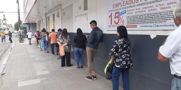 Una prolija fila de clientes aguarda su turno para ingresar al supermercado\u002E