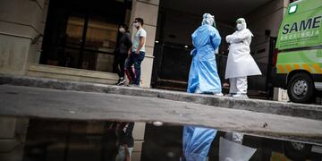 AME3606\u002E BUENOS AIRES (ARGENTINA), 20/07/2020\u002E- Una pareja pasa frente a personal médico con trajes de bioseguridad el primer día de la flexibilización de la cuarentena obligatoria por el COVID-19 este lunes en Buenos Aires (Argentina)\u002E La ciudad de Buenos Aires y su populosa área metropolitana (AMBA), junto a otras localidades con alta circulación de coronavirus, entraron este lunes en una etapa de la cuarentena más flexible, que contempla la apertura progresiva de actividades comerciales y habilita las salidas recreativas, todo sujeto a protocolos\u002E EFE/Juan Ignacio Roncoroni