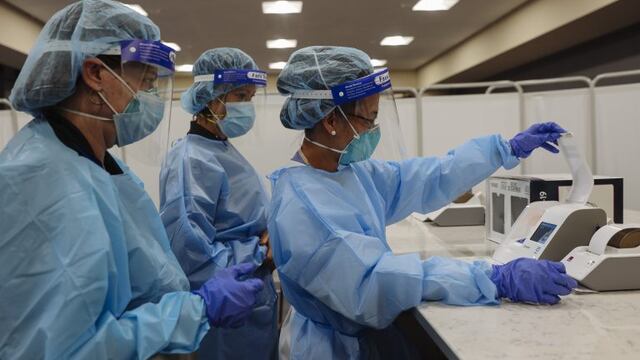 Healthcare workers wearing personal protective equipment (PPE) prepare an Abbott Laboratories ID NOW rapid test machine during a United Airlines Covid-19 test pilot program at Newark Liberty International Airport in Newark, New Jersey, U\u002ES\u002E, on Monday, Nov\u002E 16, 2020\u002E From November 16 through December 11, the United Airlines will offer rapid tests to every passenger over 2 years old and crew members on board select flights from Newark Liberty International Airport to London Heathrow, free of charge\u002E Photographer: Angus Mordant/Bloomberg