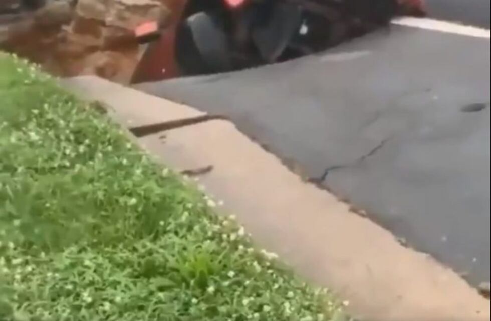 Un bache gigante se abrió en la calle y se "llevó" un auto que estaba estacionado
