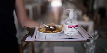 A waitress carries menus and hand sanitizer at a seafood restaurant in Marseille, southern France, Tuesday, June 2, 2020\u002E The French way of life resumes Tuesday with most virus-related restrictions easing as the country prepares for the summer holiday season amid the pandemic\u002E (AP Photo/Daniel Cole)