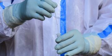 A health worker wearing a Personal Protective Equipment (PPE) suit inserts a swab sample in a tube after a Rapid Antigen Test (RAT) for the Covid-19 coronavirus on the roadside in Allahabad on August 30, 2020\u002E (Photo by SANJAY KANOJIA / AFP)