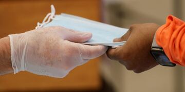 Lakewood Chapel Pastor John Elleson, left, hands a mask to Stephen Scales at Lakewood Chapel in Arlington Heights, Ill\u002E, Saturday, April 18, 2020, during the coronavirus outbreak\u002E (AP Photo/Nam Y\u002E Huh)