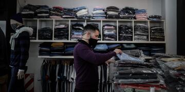 AME5200\u002E BUENOS AIRES (ARGENTINA), 08/06/2020\u002E- Un hombre acomoda ropa en su local hoy lunes, luego que el gobierno permitiera la apertura de zapaterías y locales textiles en Buenos Aires\u002E Buenos Aires, la ciudad más afectada por el coronavirus en Argentina, autoriza desde este lunes reabrir sus puertas los comercios barriales de indumentaria y calzado, con medidas de distanciamiento pero sin probadores y, aunque se mantienen restringidas las celebraciones religiosas, se podrán transmitir ceremonias desde los templos, sin público y vía internet, al igual que ocurre con los espectáculos culturales\u002E EFE/Juan Ignacio Roncoroni