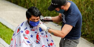 QUI01\u002E QUITO (ECUADOR), 24/04/2020\u002E Un peluquero venezolano corta el cabello a clientes en la puerta de sus hogares, este viernes en Quito (Ecuador), para obtener ingresos en medio de la cuarentena obligatoria y masiva a la que está sometido el país\u002E Algunos ecuatorianos y extranjeros residentes buscan formas de obtener ingresos, ante el confinamiento de más de un mes por la expansión del contagio de la pandemia del COVID-19 en Ecuador\u002E EFE/José Jácome