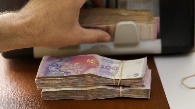 A person counts Argentine pesos from a client buying U.S. dollars, at an illegal money exchange location in Buenos Aires, Argentina, Thursday, Dec. 17, 2015. Argentina's currency sharply devalued against the U.S. dollar on Thursday as the new administrati