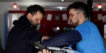 In this May 30, 2017 photo, Gino Tubaro, right, fits a prosthetic arm on Juan Pablo Pelaez in Buenos Aires, Argentina\u002E Pelaez is now able to play his beloved trumpet thanks to the new arm\u002E (AP Photo/Natacha Pisarenko) buenos aires Juan Pablo Pelaez Gino Tubaro taller del joven emprendedor que hace protesis ortopedicas en impresoras 3D joven espera para terminar una pieza para su protesis de brazo protesis de mano maratones donde se reparte a los niños de forma gratuita