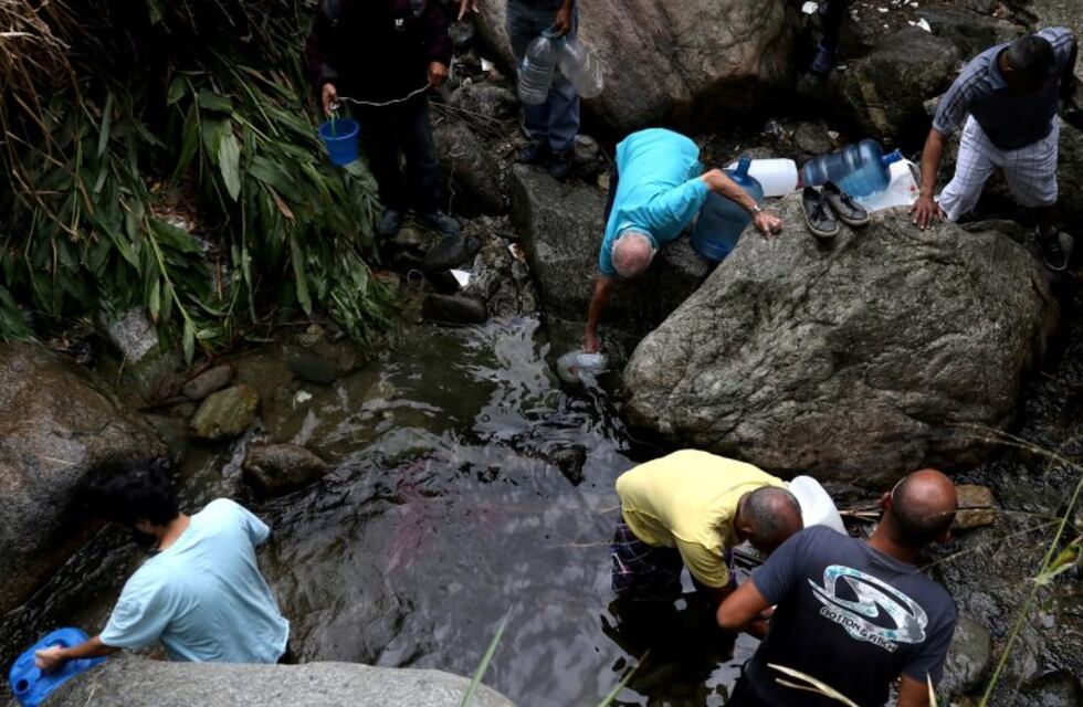 Por la escasez, los caraqueños juntan agua de un río contaminado