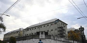 Police officers walk outside Villa Devoto prison as inmates appear from a hole on the destroyed roof of the prison during a riot in demand of preventive measures against the spread of COVID-19 after a case of the novel coronavirus was confirmed inside the facility, in Buenos Aires on April 24, 2020\u002E (Photo by Juan MABROMATA / AFP)