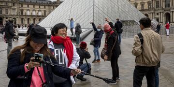 A visitor in a face mask poses for photographs outside the Louvre Museum which is closed due to staff worries over the coronavirus outbreak in Paris, France, on Monday, March 2, 2020\u002E Group of Seven finance ministers will hold a teleconference this week to coordinate their response to the coronavirus outbreak, France’s Finance Minister Bruno Le Maire said Monday\u002E Photographer: Adrienne Surprenant/BloombergA