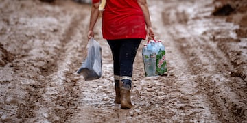 Una mujer con agua y botas camina por las calles embarradas tras las inundaciones en Valencia, España.