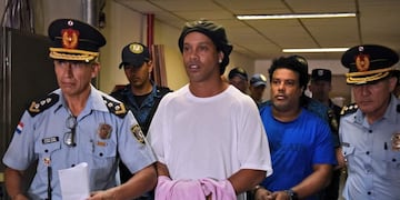 (FILES) In this file photo taken on March 07, 2020 Brazilian retired football player Ronaldinho (C) and his brother Roberto Assis (R) arrive at Asuncion's Justice Palace to appear before a public prosecutor who will decide whether to grant them bail or not following their irregular entry to the country, in Asuncion\u002E - A judge in Paraguay on April 7, 2020 ordered the release of Brazilian football great Ronaldinho and his brother into house arrest at an Asuncion hotel\u002E They were jailed almost exactly a month ago to await trial on charges of using false passports to enter Paraguay\u002E Lawyers for the men posted bail of $1\u002E6 million\u002E (Photo by Norberto DUARTE / AFP)