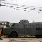 A man sits as a police armored vehicle is seen during an operation against drug dealers in City of God or City of God slum in Rio de Janeiro, Brazil, November 23, 2016. REUTERS/Ricardo Moraes