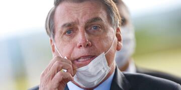 FILE PHOTO: FILE PHOTO: Brazil's President Jair Bolsonaro adjusts his mask as he leaves Alvorada Palace, amid the coronavirus disease (COVID-19) outbreak in Brasilia, Brazil May 13, 2020\u002E REUTERS/Adriano Machado/File Photo/File Photo
