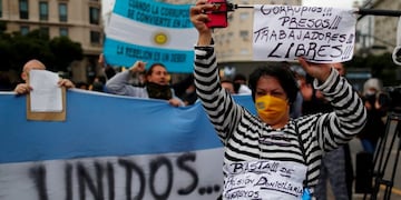 An anti-quarantine demonstrator wearing a prisoner's clothing holds a placard that reads \