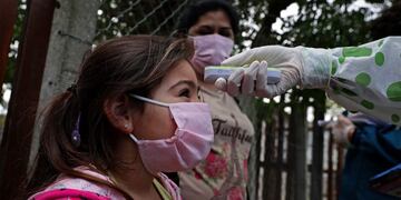 A girl from Altos de San Lorenzo neighbourhood, near the city of La Plata, 65 km from Buenos Aires, has her temperature taken by a health worker on May 24, 2020 amid the COVID-19 coronavirus pandemic\u002E - While the number of COVID-19 cases in Argentina has raised to more than 11,000, the \